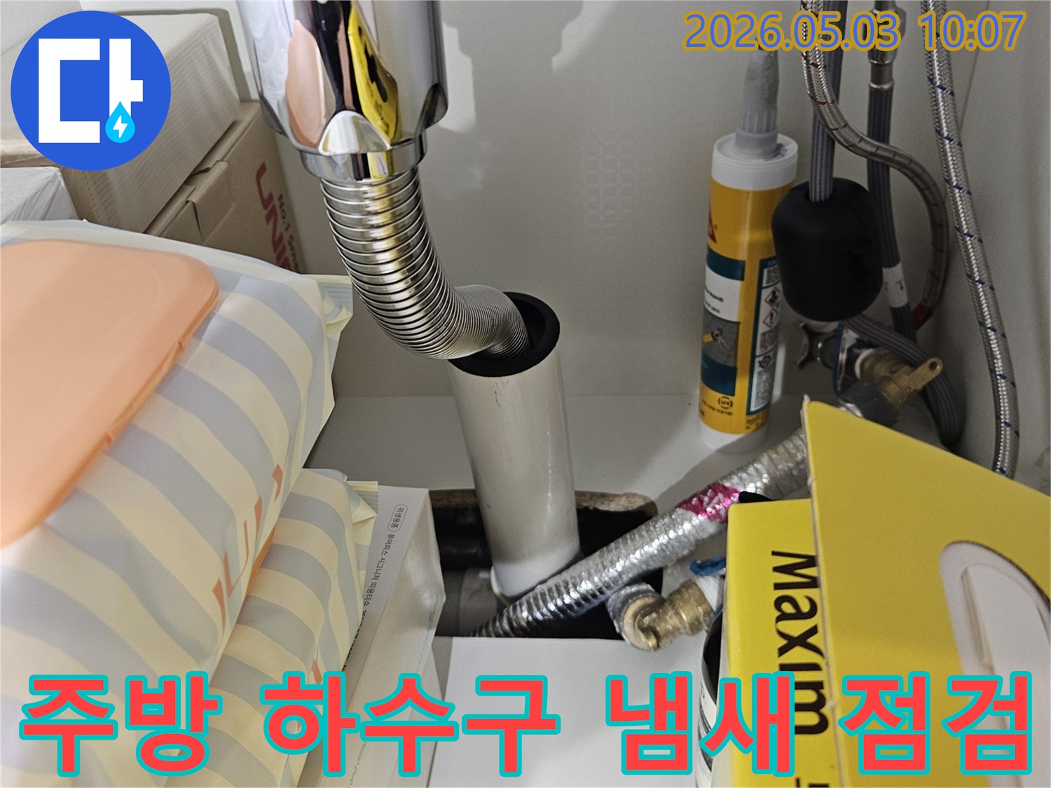 주방 싱크대 하부의 배수관 연결 부위를-정밀하게 점검하여 하수구 냄새와 누수 원인을 찾는 모습