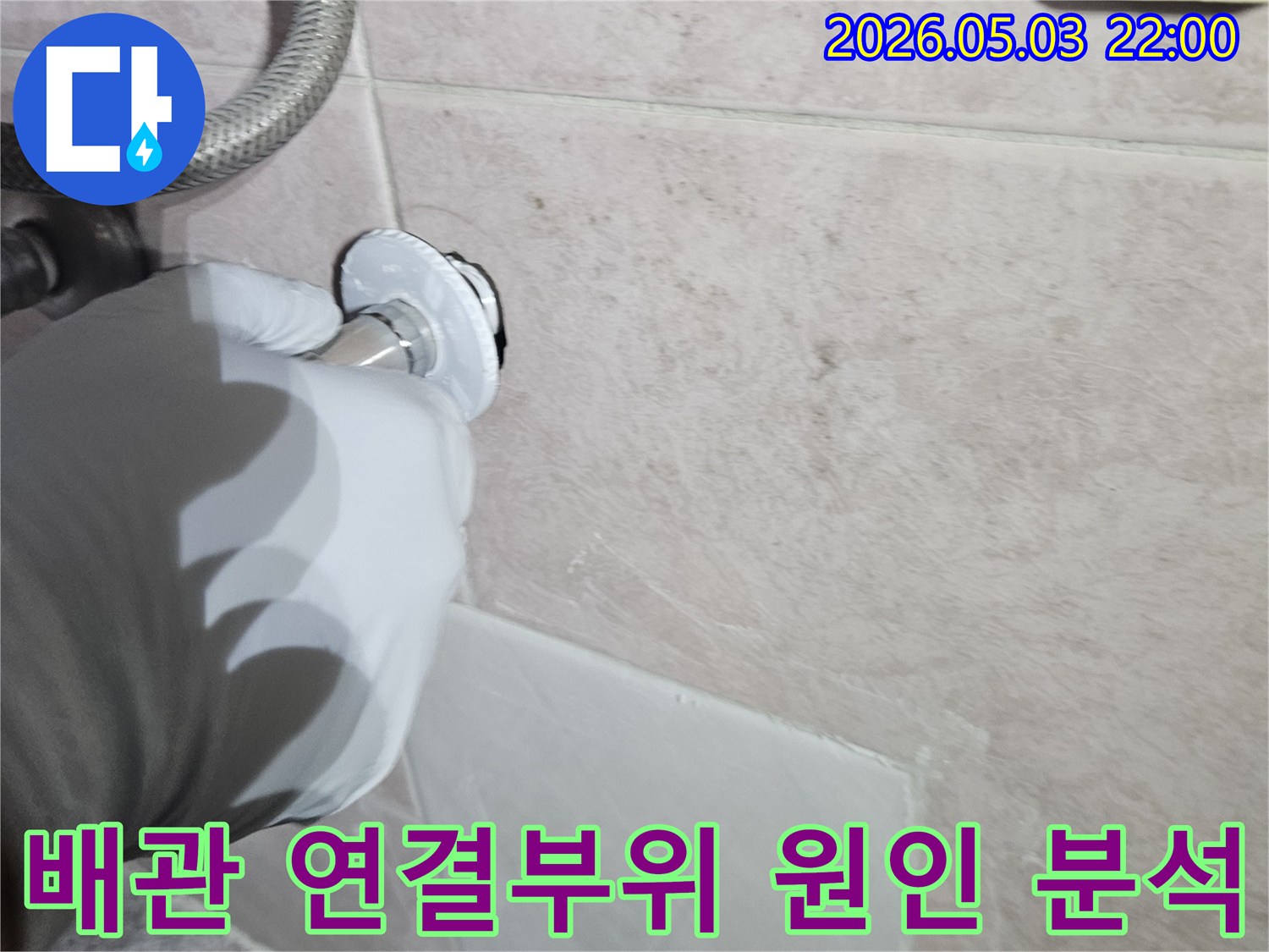전문 엔지니어가 흰 장갑을 착용하고-타일 벽면의 수도 배관 연결 부속을-면밀히 관찰하며-누수 원인을 분석하는 작업