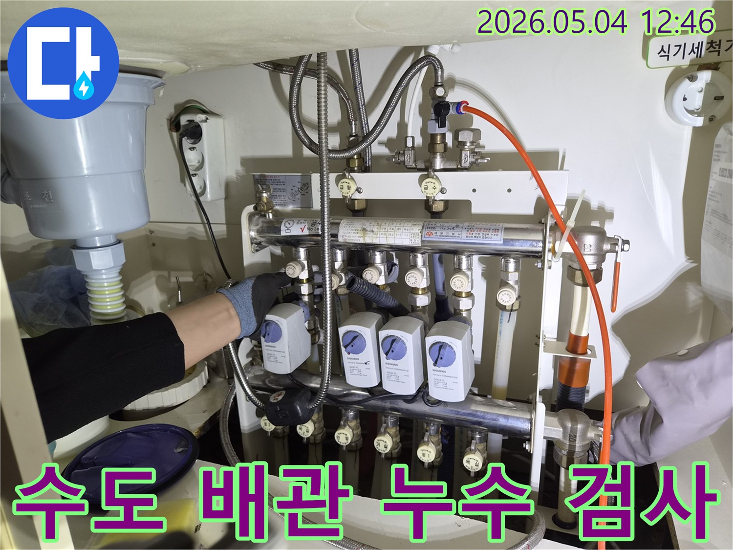 누수 엔지니어가-금호동 아파트에서-수도 배관 누수를-정밀하게 검사하기 위해-분배기에 장비를 연결하는 장면