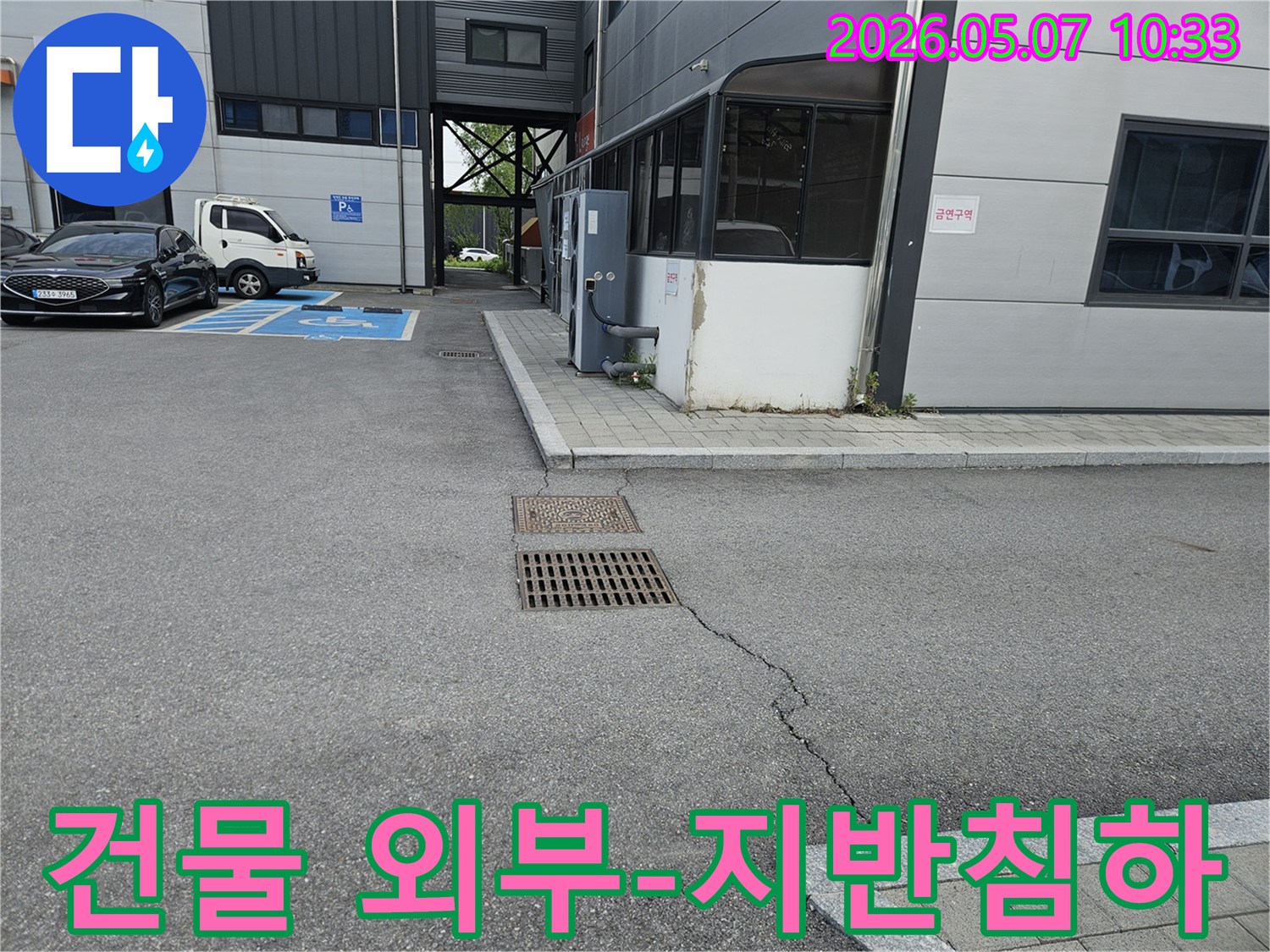 이 이미지는 의정부시 만가대길 건물의 외부 주차장에서-아스팔트 균열과-맨홀-배수구 주변의 지반 침하 현장을 보여줍니다.