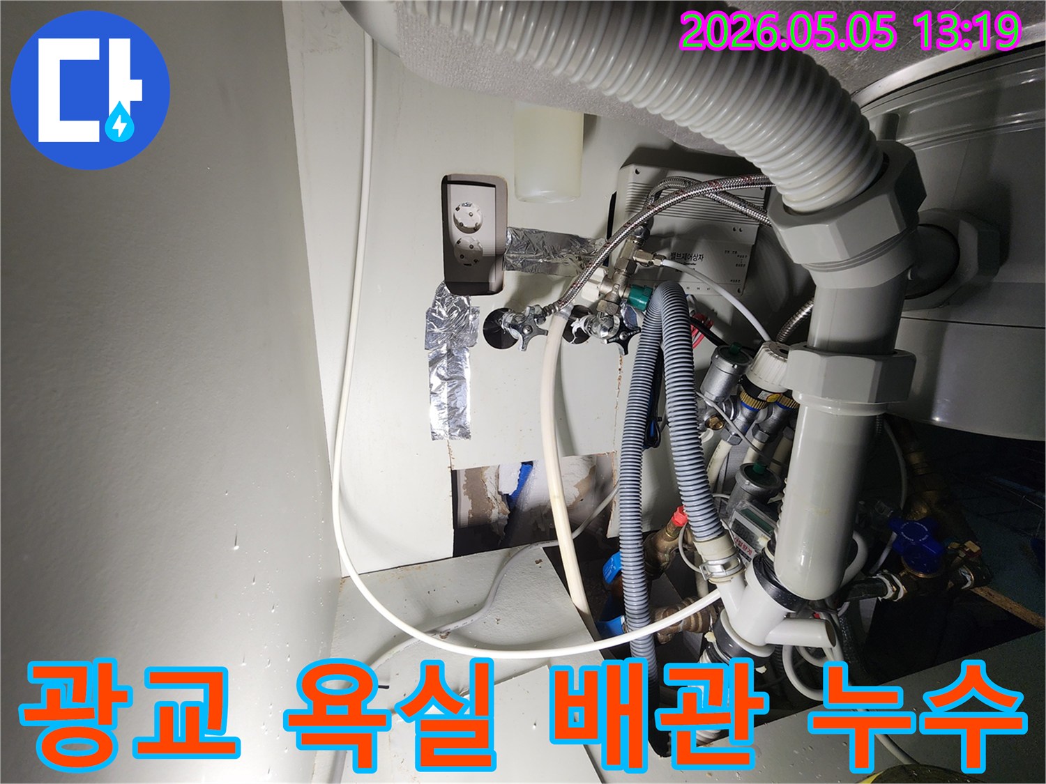 이 이미지는-수지-광교-아파트의-욕실-배관에서-발생한-누수-현장을-보여주며-벽면을-개방하여-드러난-복잡한-배관과-전기-시설-사이에서-물이-새는-모습을-촬영한-것입니다