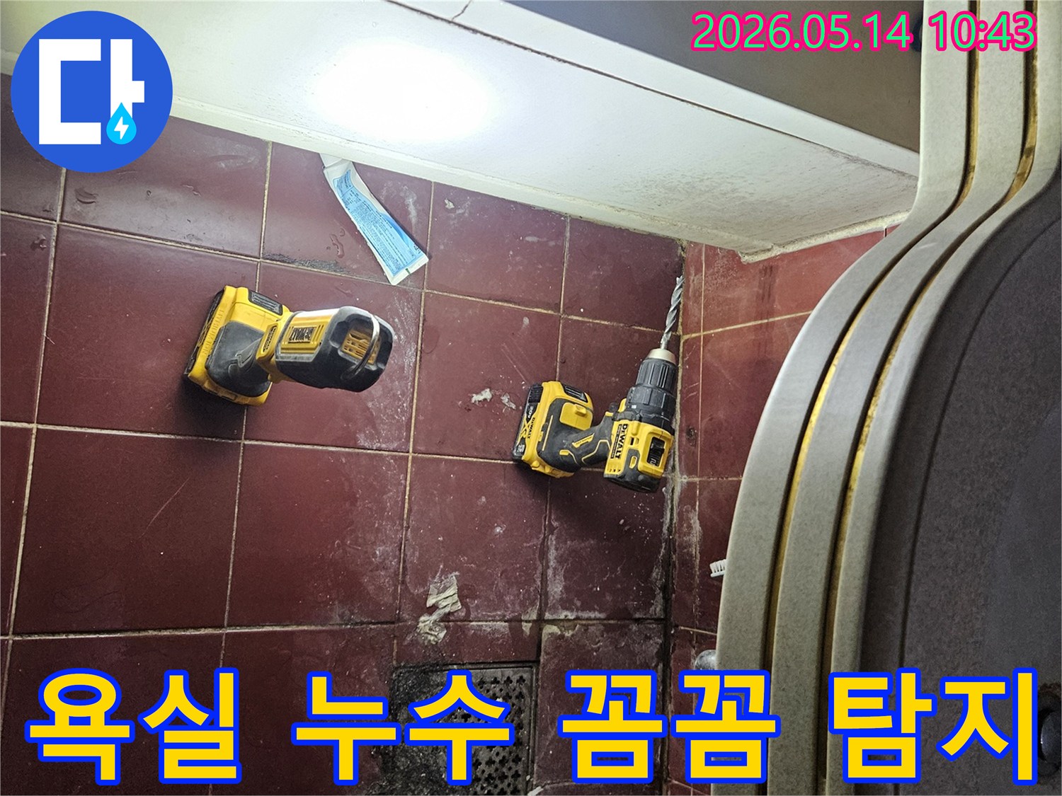 붉은 타일 바닥에 놓인 전동 드릴과 조명-꼼꼼하고 정확한 욕실 누수 탐지를 위한 준비입니다