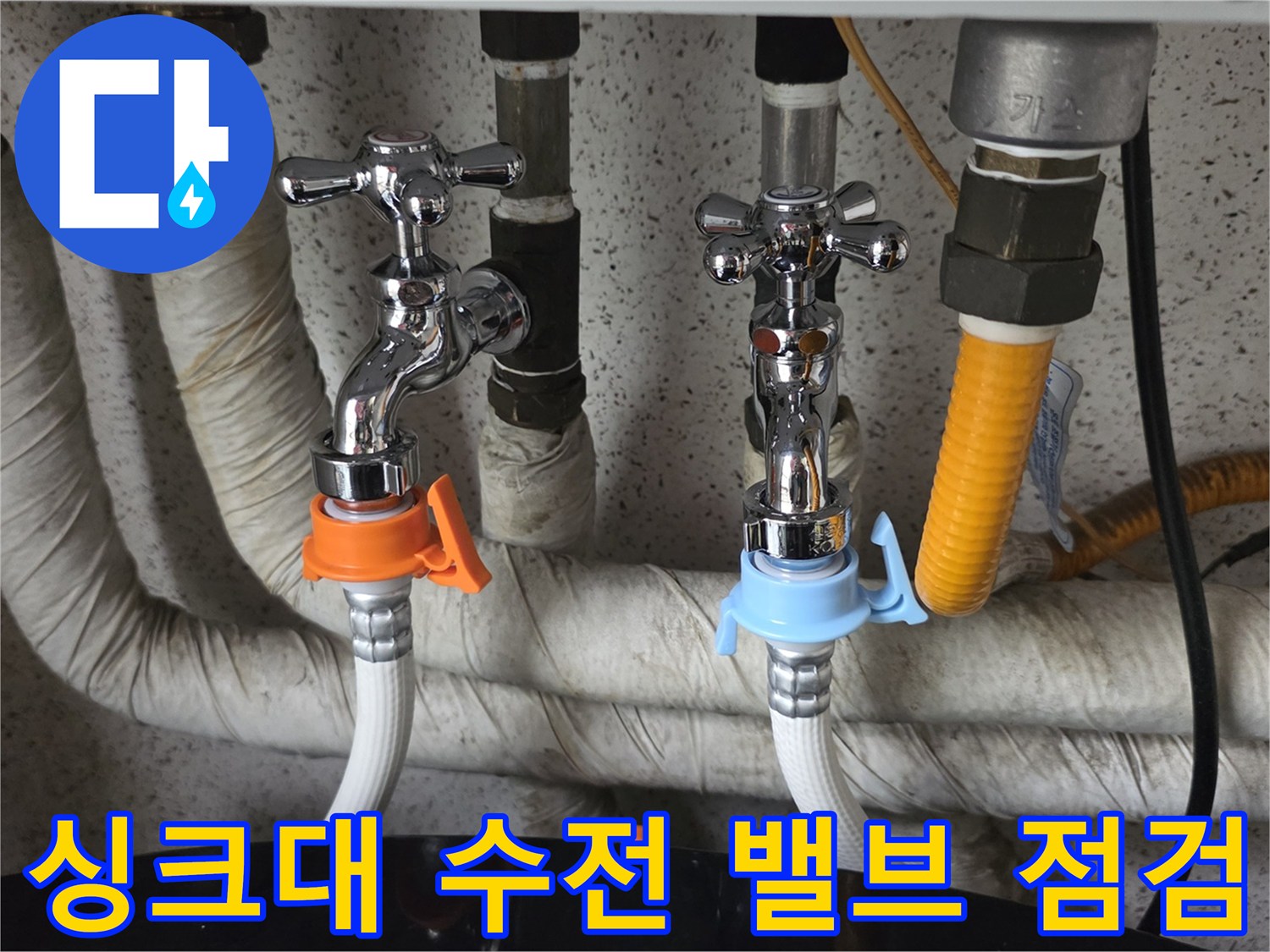 주황색 클램프가 체결된 수도꼭지와 보온재로 감싸진 배관의 근접 촬영