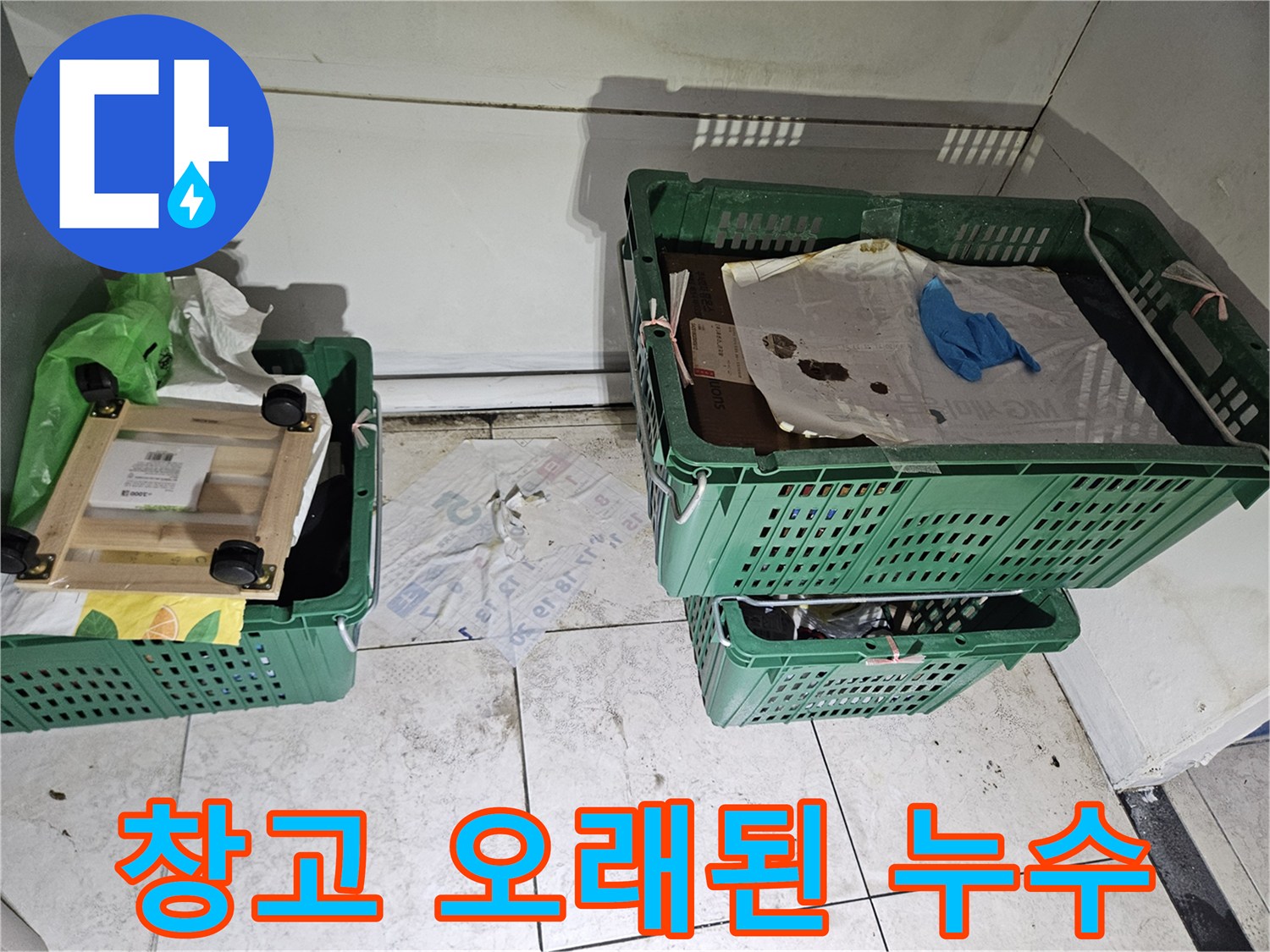물건들이-쌓여있는-창고 같은-공간의-벽면 하단과-바닥 경계에-누수로 인한-오래된 오염과-습기 흔적이-뚜렷하게-보이는-현장 사진입니다