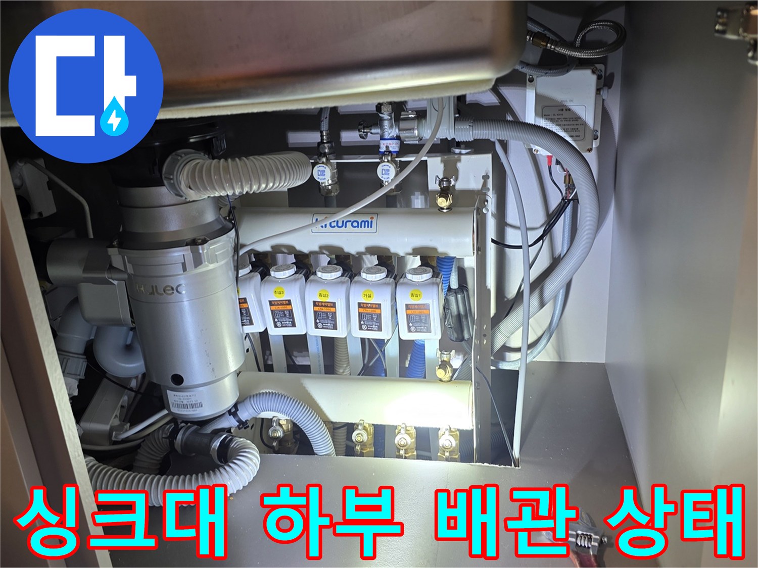 주방 싱크대 아래 분배기 밸브와 연결된 호스들의 상태를 촬영한 사진입니다.