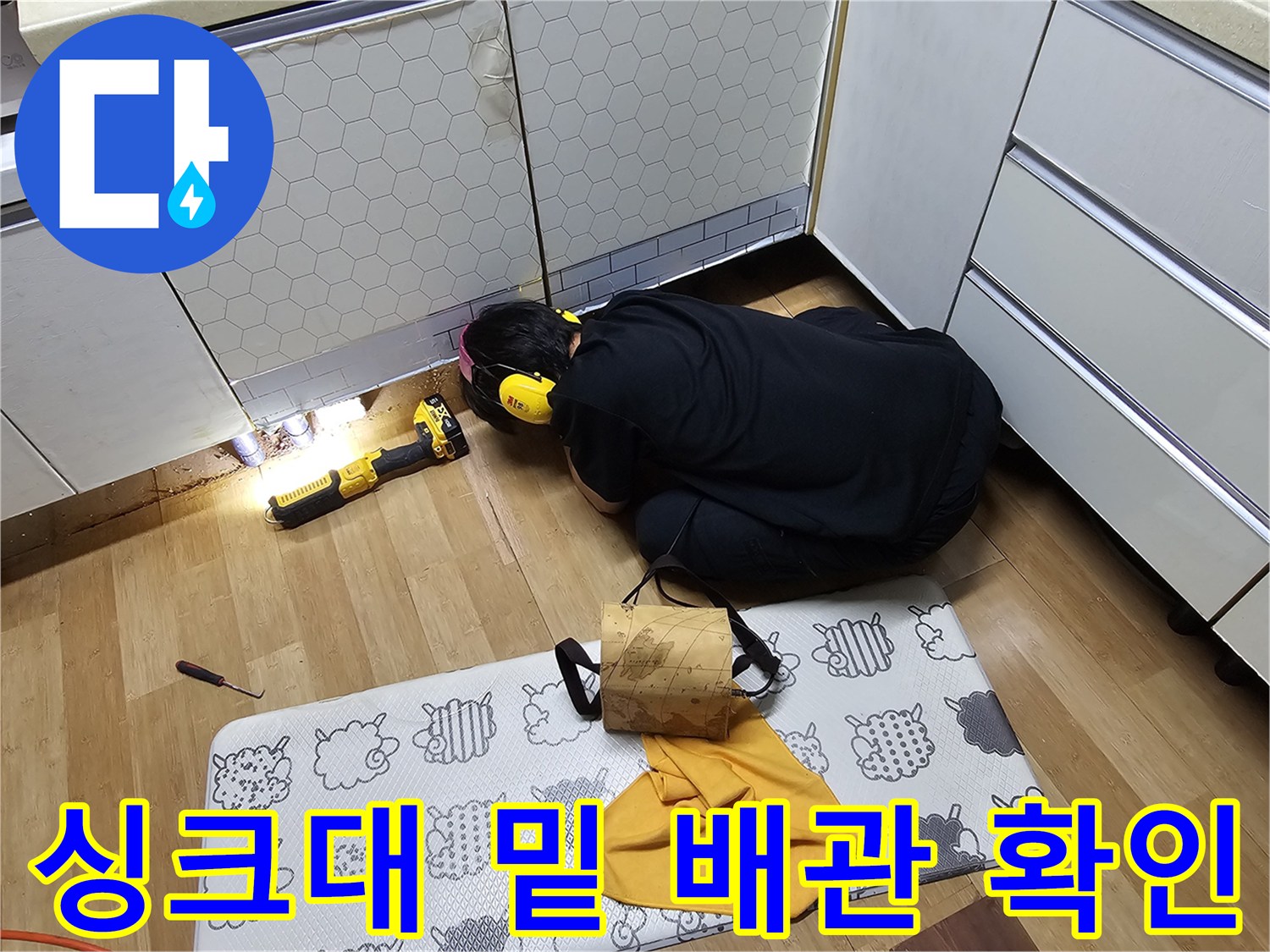싱크대 하단 배관의 물샘 지점을 찾기 위해 점검하는 작업자
