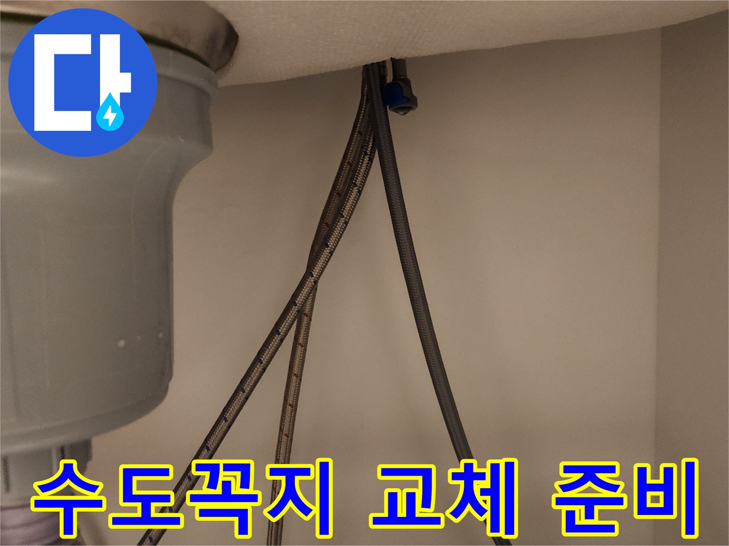 노후된 수도꼭지를 교체하기 위해 싱크대 아래 급수관을 분리하는 준비 작업을 보여줍니다.