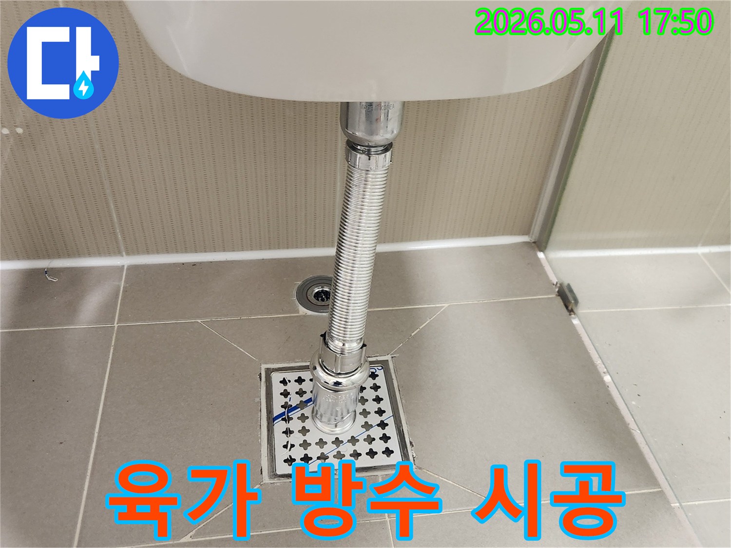 욕실 바닥에-새롭게 설치된-육가 배수망과-세면대 배수관의-안전하고-방수 처리된-연결 상태를-보여줍니다.