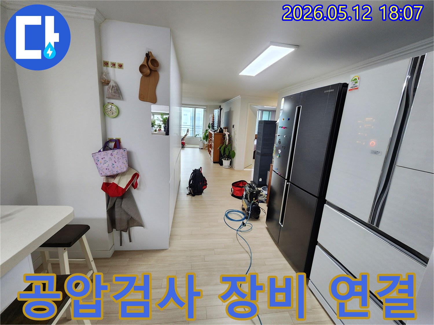 누수 탐지를 위한 공압검사 장비가-거실 바닥에 놓여 있고-호스가 연결된 상태