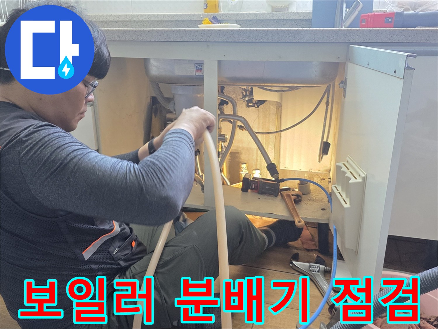 싱크대 밑 공간-분배기 연결 부위의 누수를 확인하는 작업자