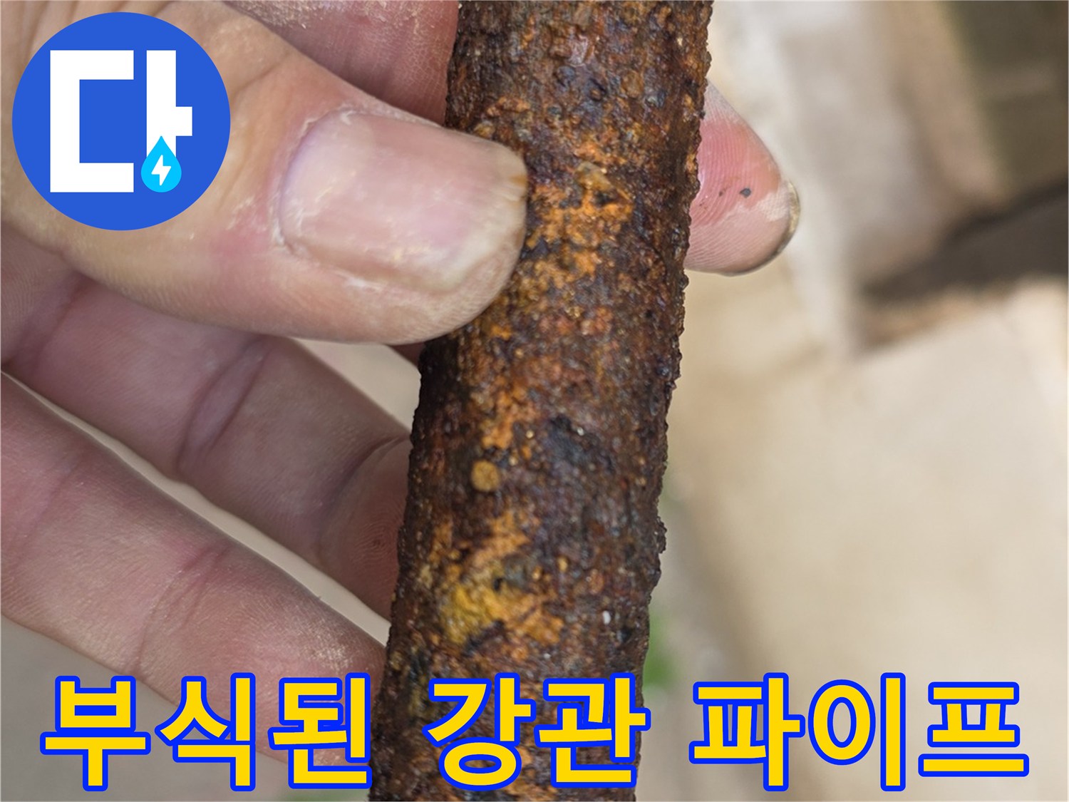 손으로 잡고 있는-심하게 부식되어 붉게 녹슨-노후 철관