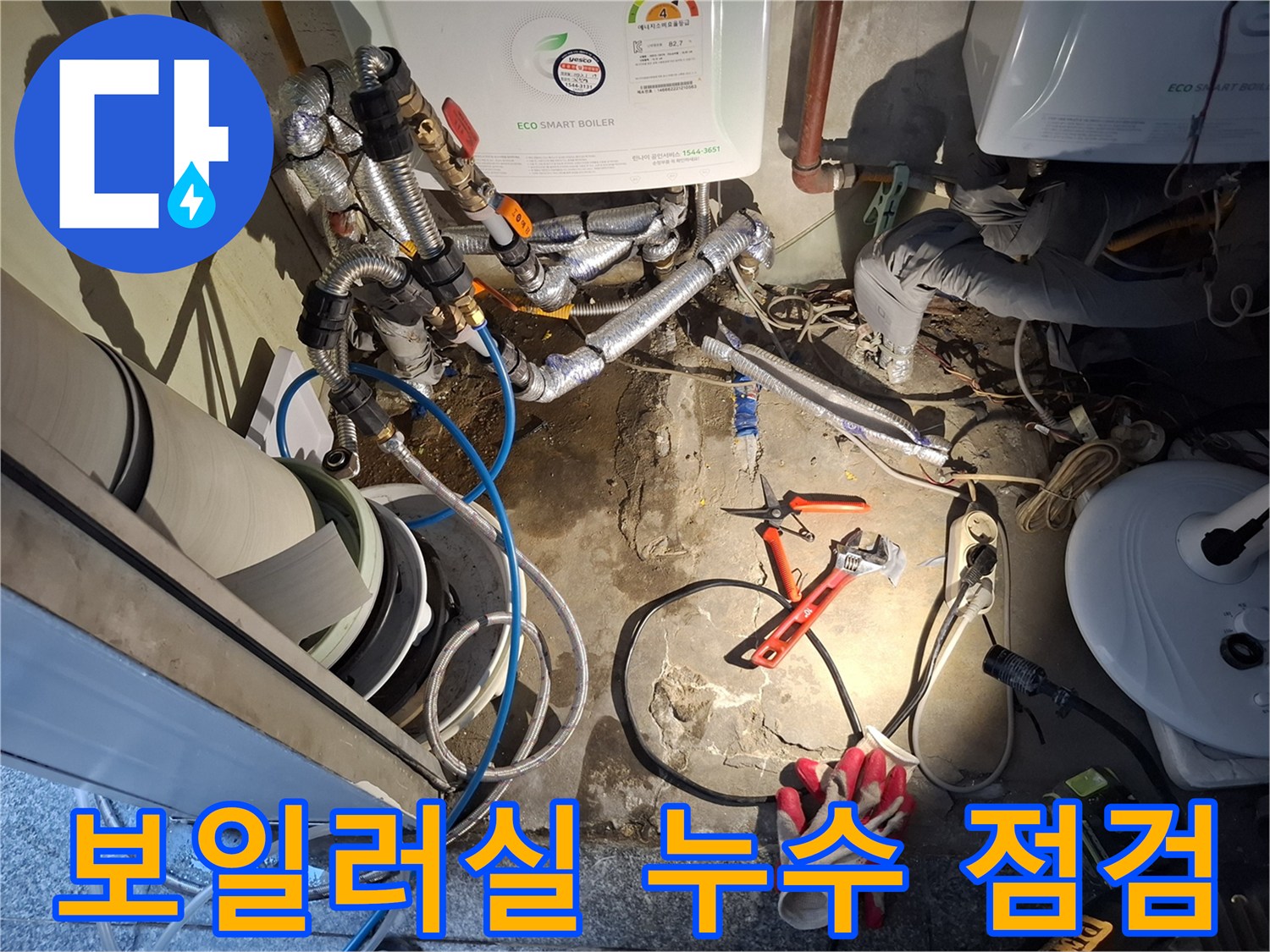 보일러 아래쪽 배관 연결부와 작업용 펜치 및 장갑