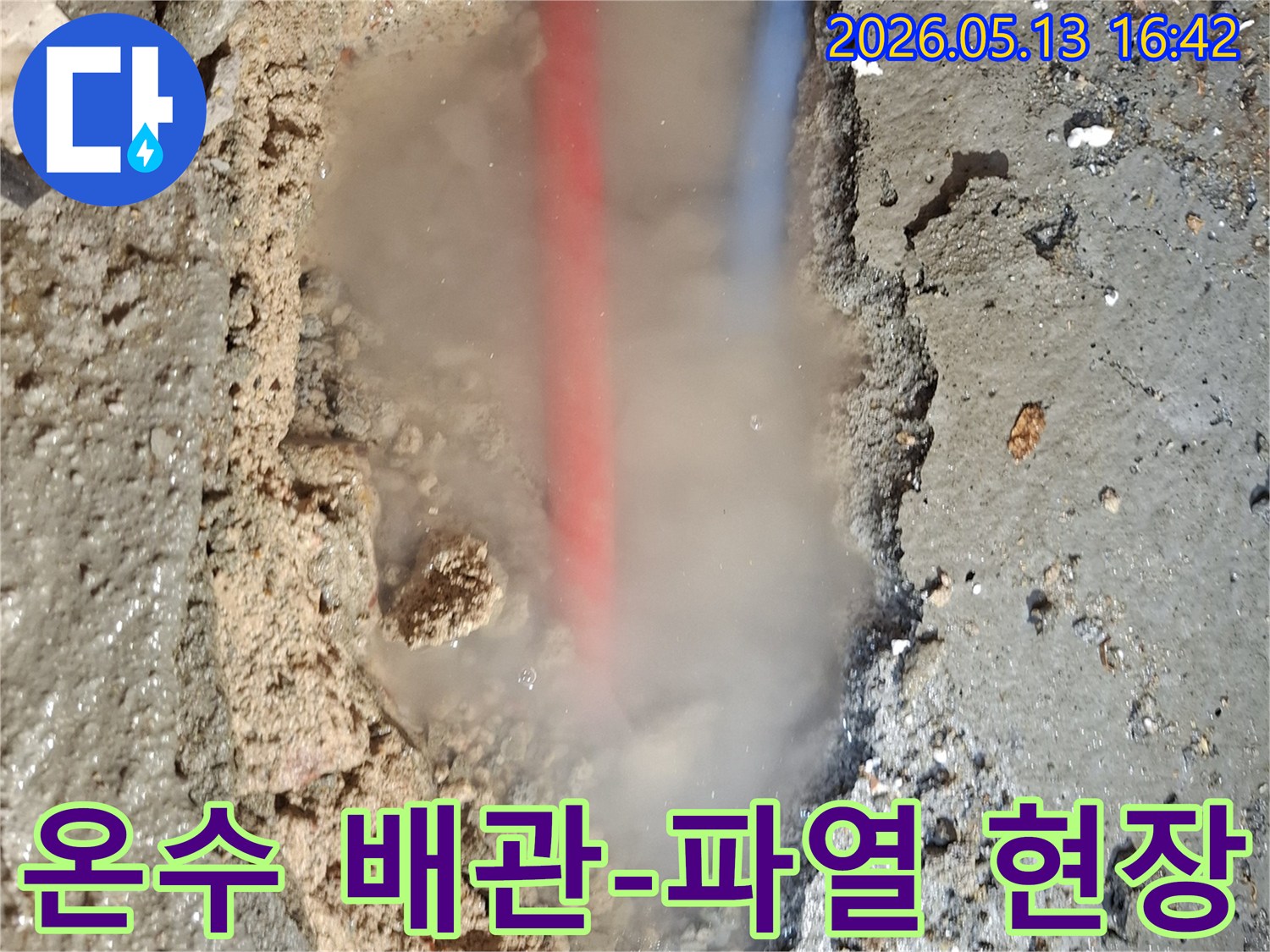 파헤쳐진 콘크리트 바닥 아래-붉은색과 푸른색 배관이 보이고-흙탕물과 함께-수증기가 솟아오르는-심각한 누수 상황을 담은 이미지