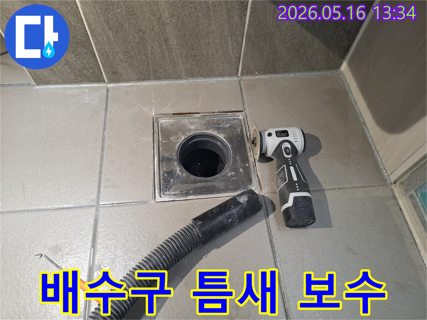 누수 엔지니어가 욕실 배수구의 틈새 누수를 해결하기 위해-전동 공구로 주변을 정리하고-흡입 호스로 잔해물을 제거하는 중입니다