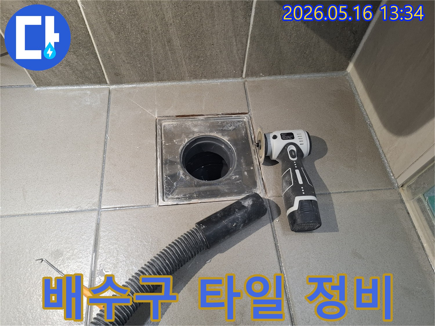 전문 엔지니어가 욕실 배수구 주변의 타일 틈새 누수를 해결하기 위해-전동 공구로 표면을 정리하는 작업을 진행 중입니다