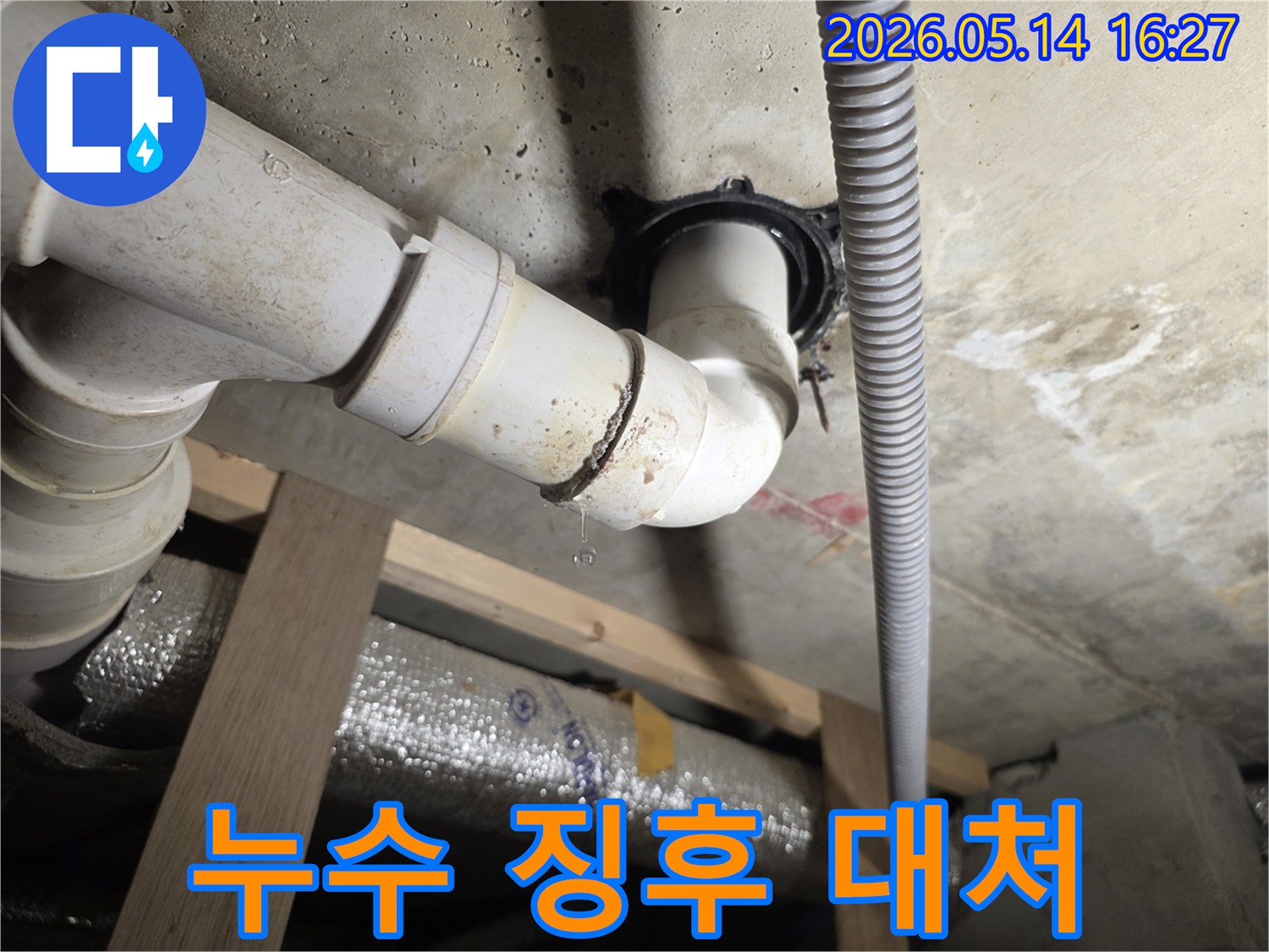 천장 아래 배관 이음새에서 물방울이 떨어지는-생활 속에서 발견할 수 있는 누수 징후와 대처법을 설명하는 데 사용될 수 있는 사진