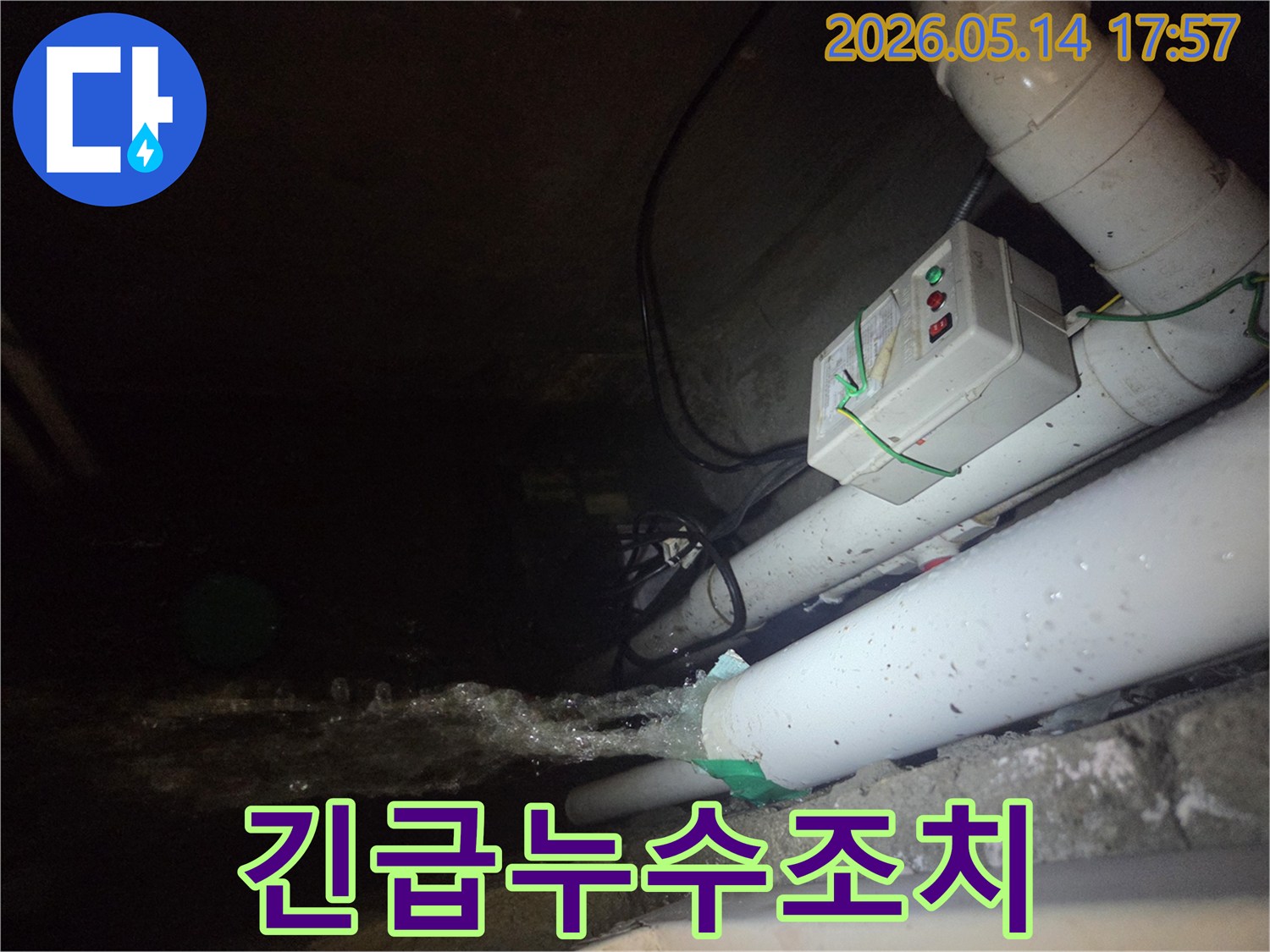 어두운 지하 공간에서-파이프에서 물이 강하게 뿜어져 나오는-긴급 누수 현장을 보여주는 이미지입니다-전기 제어 박스와 다른 배관들이 함께 보입니다.