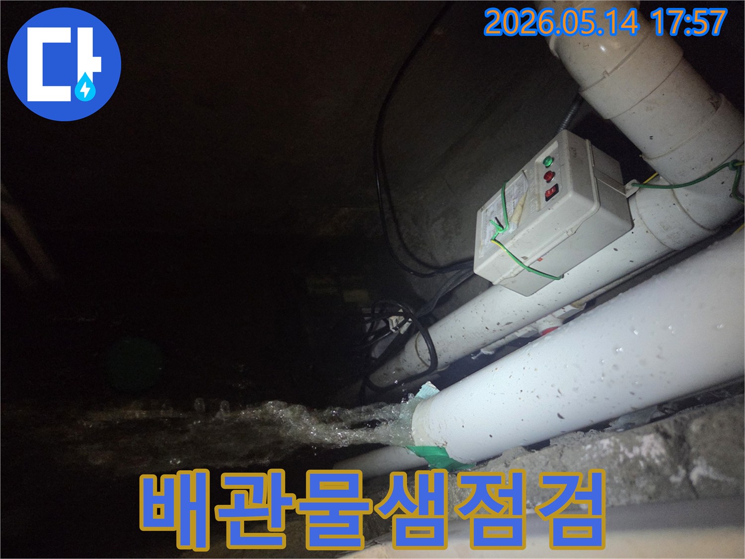 어두운 지하 공간에서-파이프에서 물이 강하게 뿜어져 나오는-누수 현장을 정밀하게 점검하는 모습입니다-전기 제어 박스와 배관들이 주변에 보입니다.