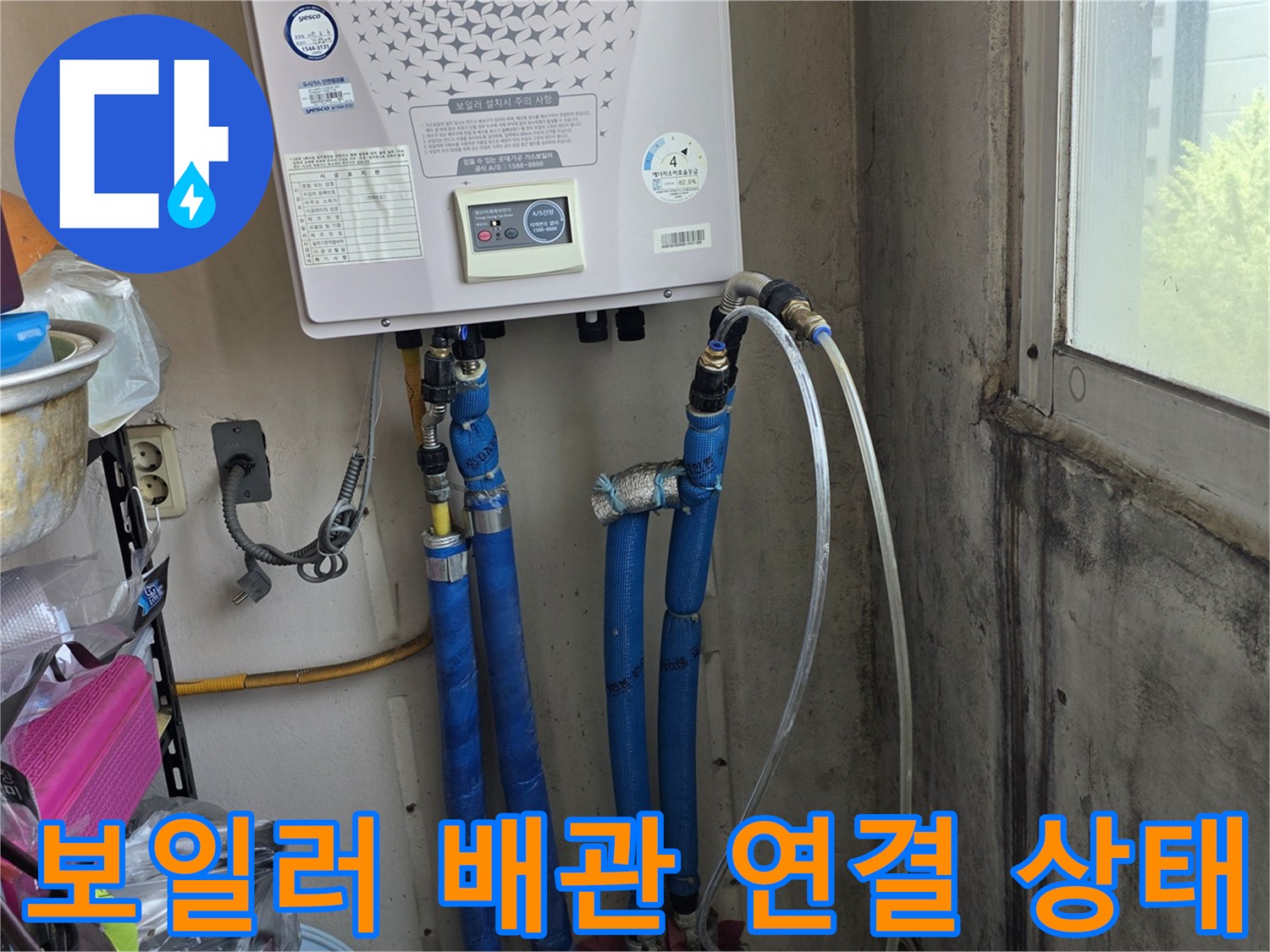 보일러 하단-연결된 파란색 주름관과 급수 배관의 모습