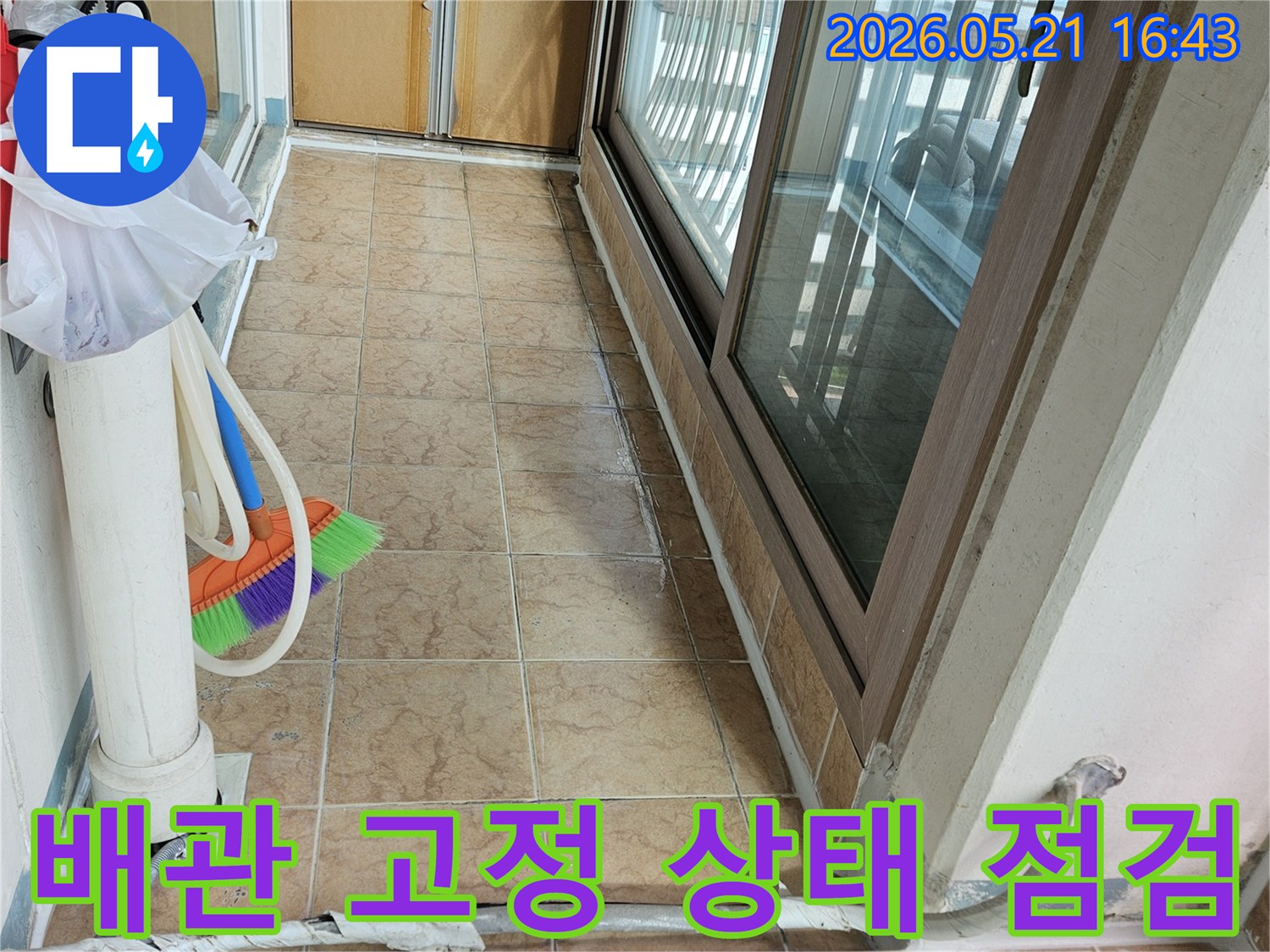 아파트 베란다의 배관 고정 상태와-주변 타일 벽면을 보여주며-배관 흔들림으로 인한 누수 여부를 점검하는 현장입니다.