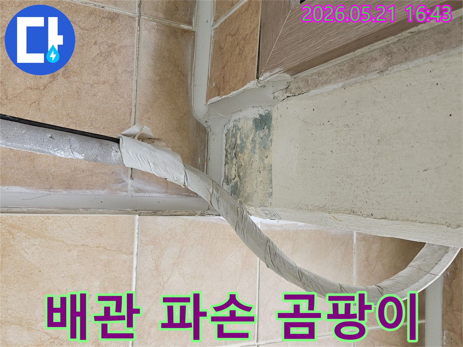 이 이미지는-포천 아파트의-벽면 하단에-발생한-녹색 곰팡이와-단열 처리된-배관의-모습을-보여주며-배관 파손-가능성을-시사합니다