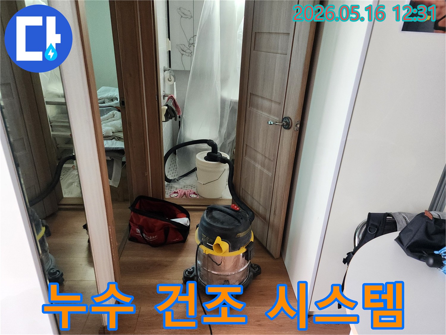 누수 수리 완료 후-바닥에 남은 물기를-전문 습식 청소기로 흡입하여-건조하는 현장 사진입니다.