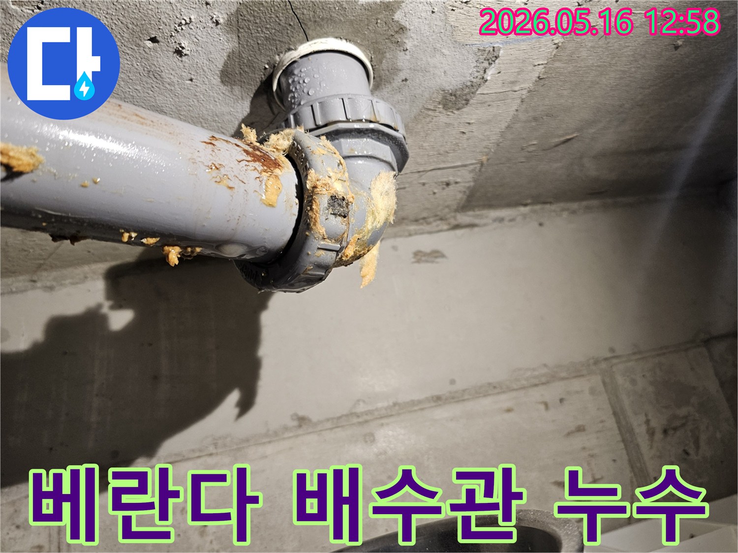 베란다-천장-아래-배수관-연결부에서-물이-새어-나와-단열재가-젖은-모습을-보여주는-누수-현장-사진