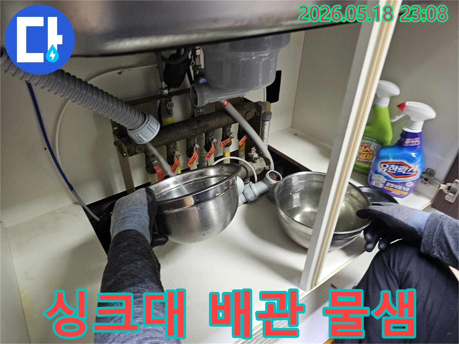 전문가가-싱크대-하부-배관에서-새는-물을-임시-그릇에-받아내며-상황을-파악하는-모습