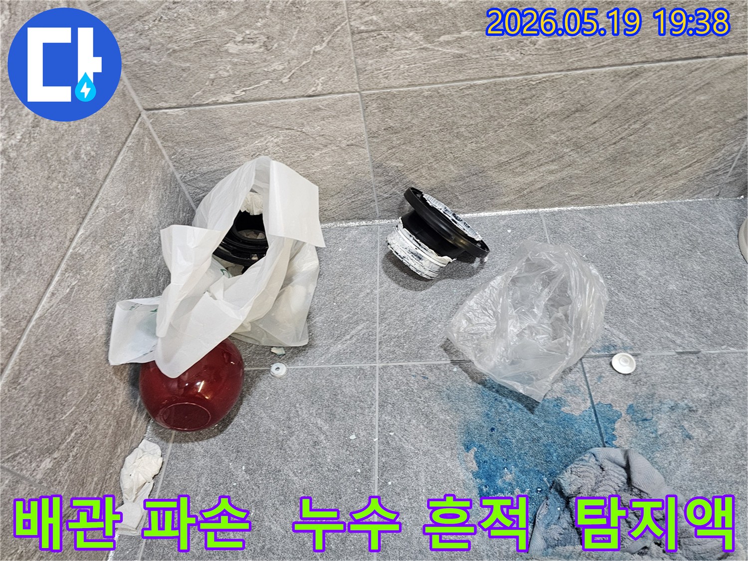 누수 탐지 현장에서-파란색 탐지액으로 확인된 배관 파손 지점과-교체될 부품들이 바닥에 놓여 있습니다