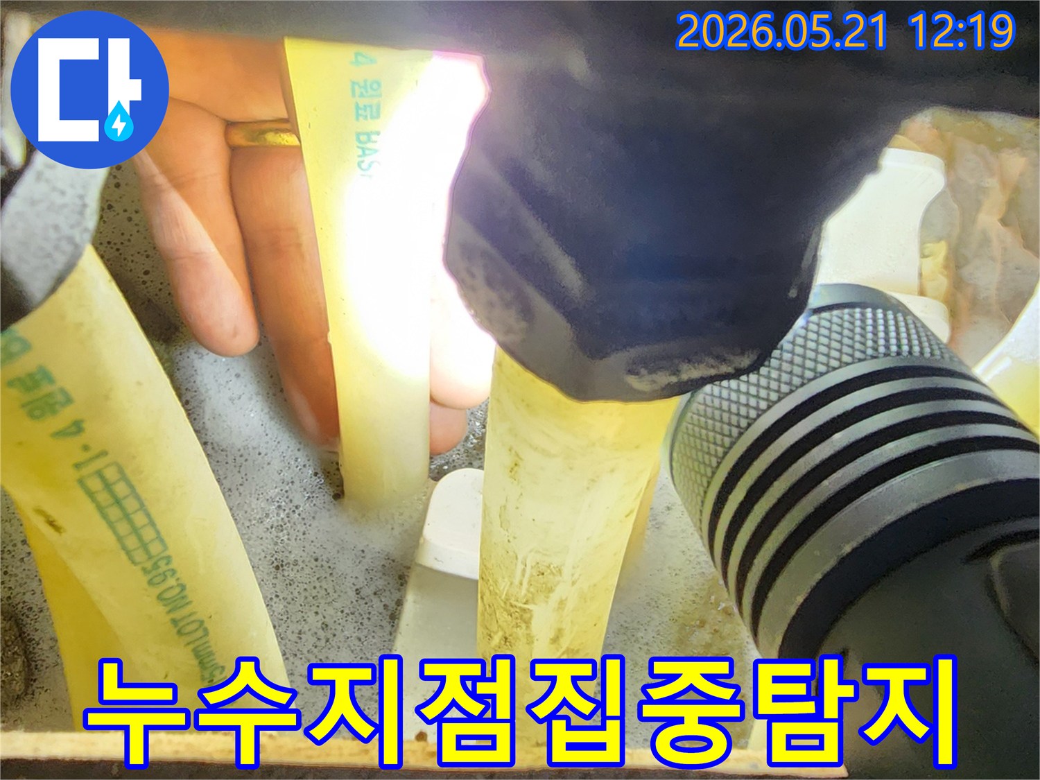 누수-엔지니어가-손전등으로-배관-주변을-집중적으로-탐지하며-누수-징후를-찾아내는-과정