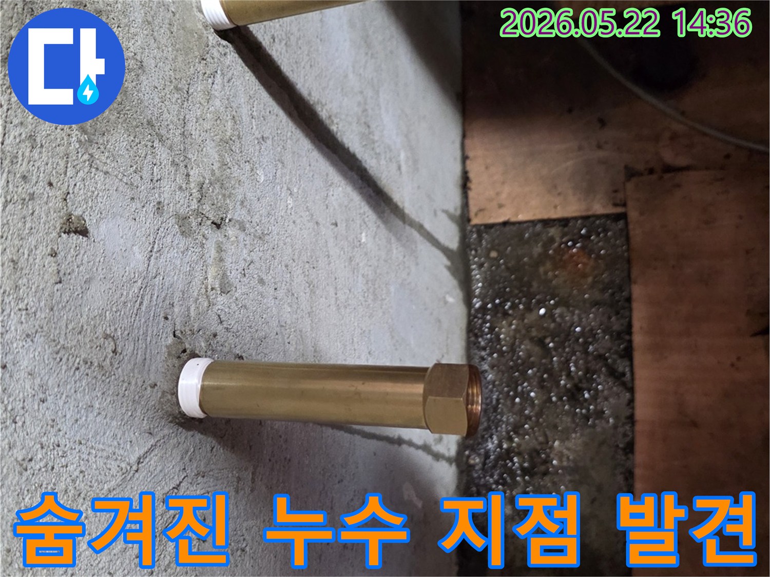 콘크리트 천장에서 돌출된 금속 배관 아래로 물이 고여있는-숨겨진 누수 지점을 정밀 탐지로 발견하는 모습입니다.
