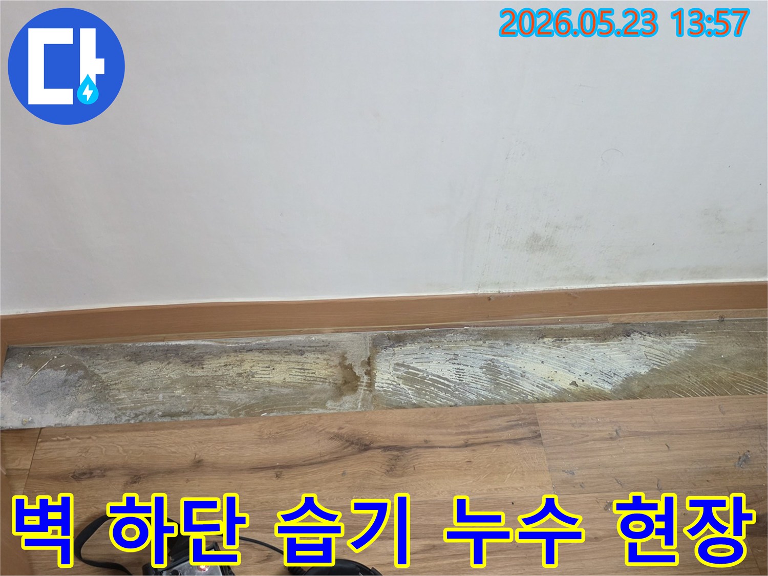 누수 탐지 장비와 함께-벽 하단에 발생한-습기와-곰팡이 흔적을-보여주는-손상된 벽면 사진