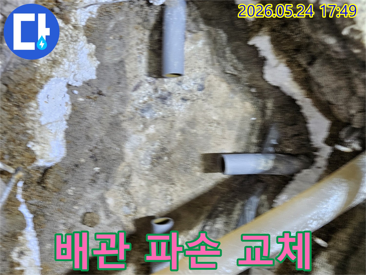 누수 공사 현장에서 파손된 배관 부위를 확인하고-교체 작업을 준비하는 모습이 담긴 사진입니다