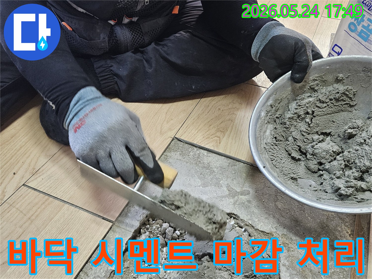 누수 보수 작업자가 장갑을 끼고 흙손으로 바닥에 시멘트 모르타르를 바르는 모습-누수 탐지 후 파손된 바닥을 복구하는 과정