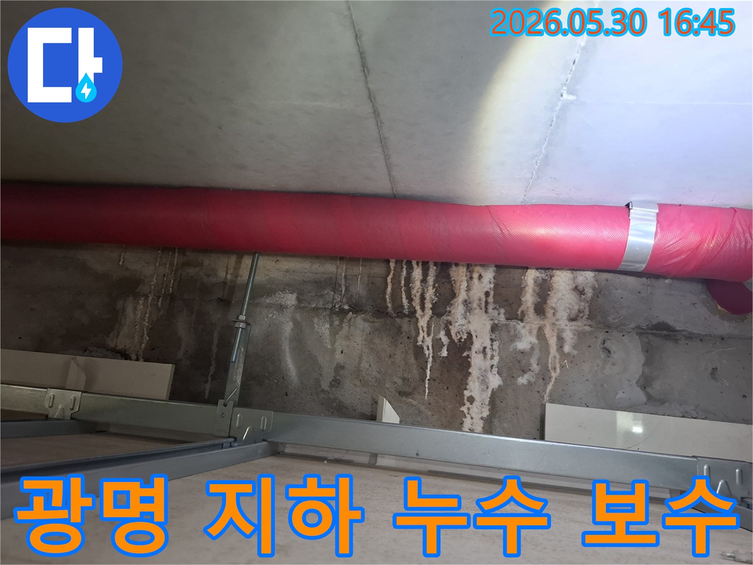 광명 아파트 지하 천장에서- 붉은 배관 아래로 보이는- 콘크리트 물자국을- 제거하고 보수하는 작업 현장