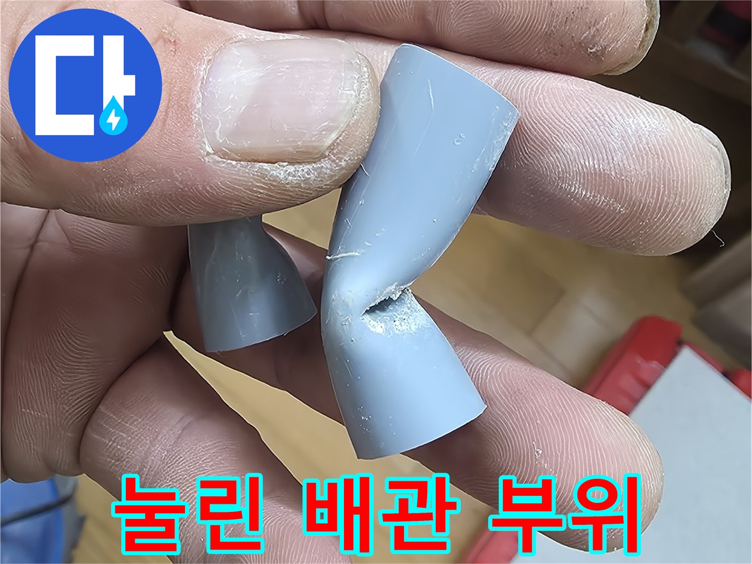 손에 들려 있는 함몰된 형태의 회색 배관 연결부