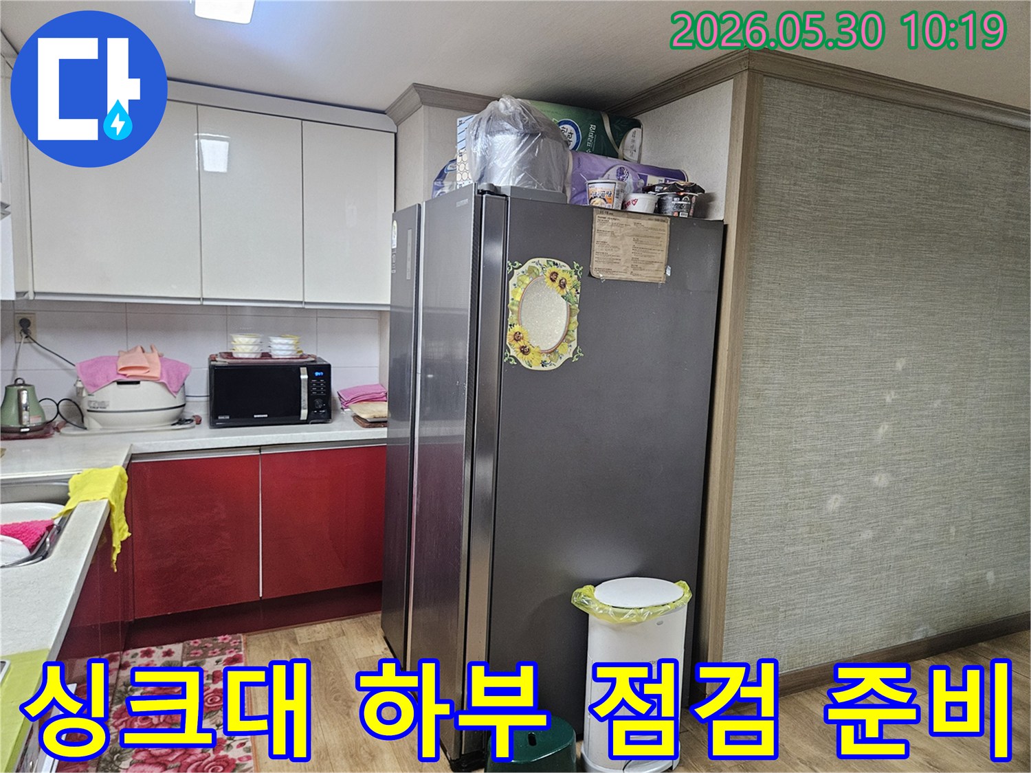 누수 엔지니어가-강동구 천호동 아파트 주방에서-싱크대 하부 누수 점검을 위해-주변을 정리하고 있습니다