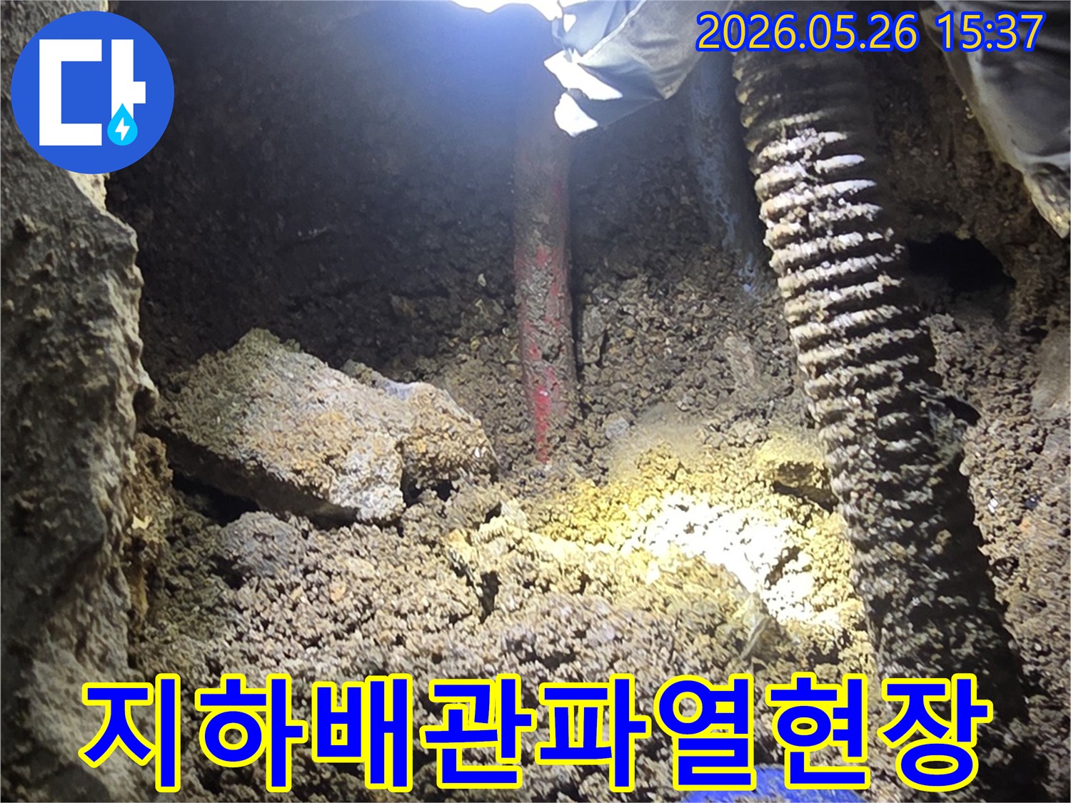 누수-탐지-전문가가-어두운-굴착-현장에서-지하-배관의-파열-지점을-손전등으로-밝혀-확인하는-모습