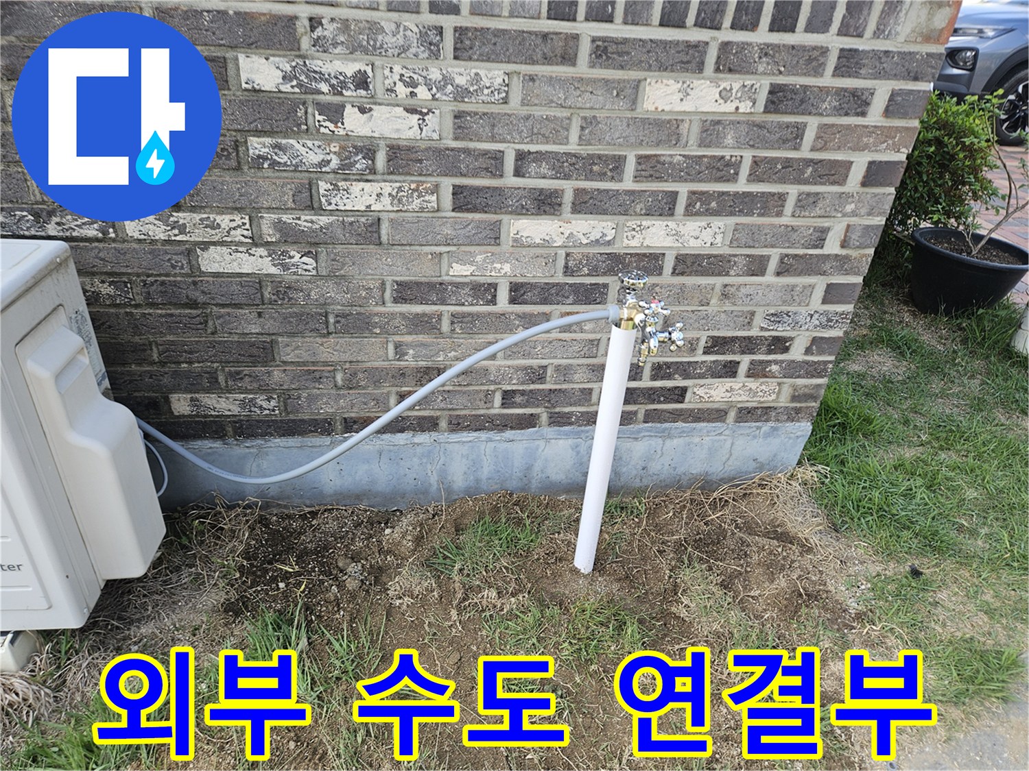 벽돌 외벽에 설치된 외부 수도꼭지와 연결 배관 모습입니다.
