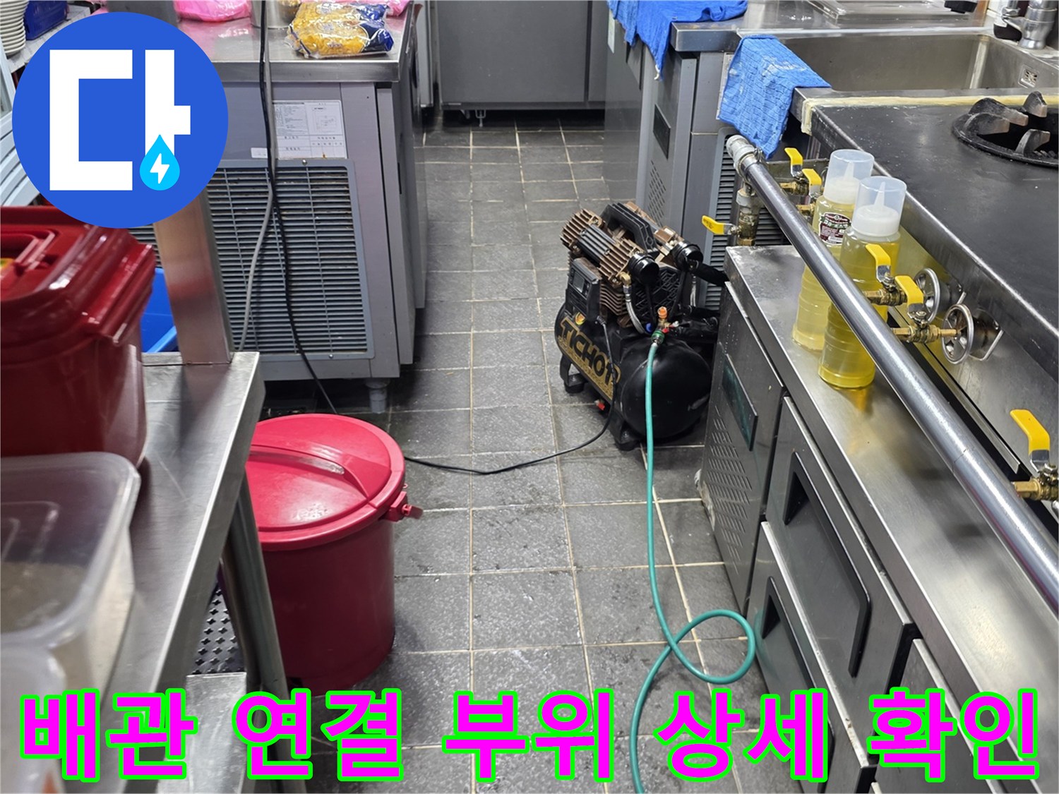 주방 조리기구 하단에 위치한 금속 배관과 노란색 밸브의 근접 촬영