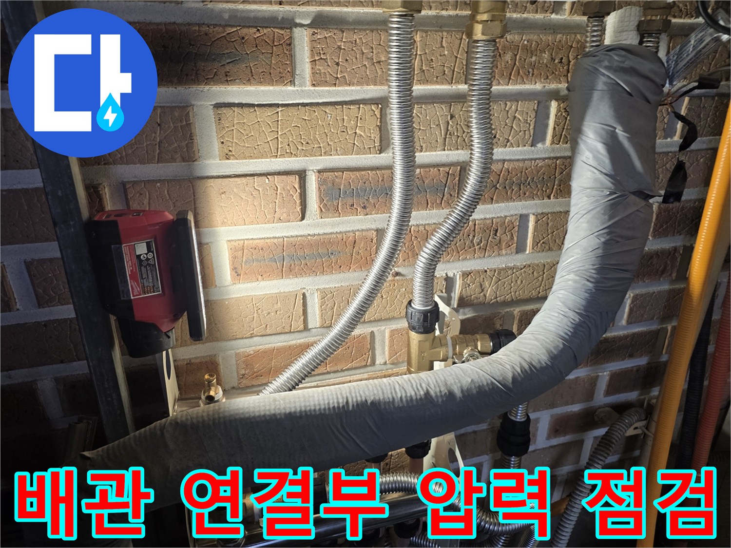 벽돌 벽면에 설치된 보일러 분배기와 주름관 상세 모습