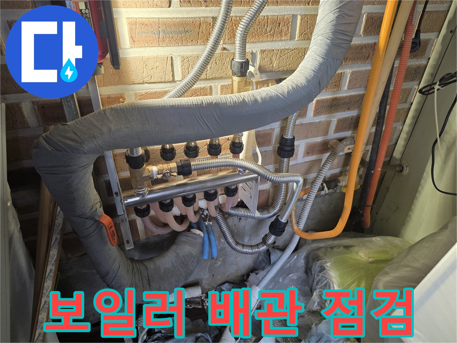 보온재로 감싸진 배관과 금속 분배기의 연결 모습입니다.