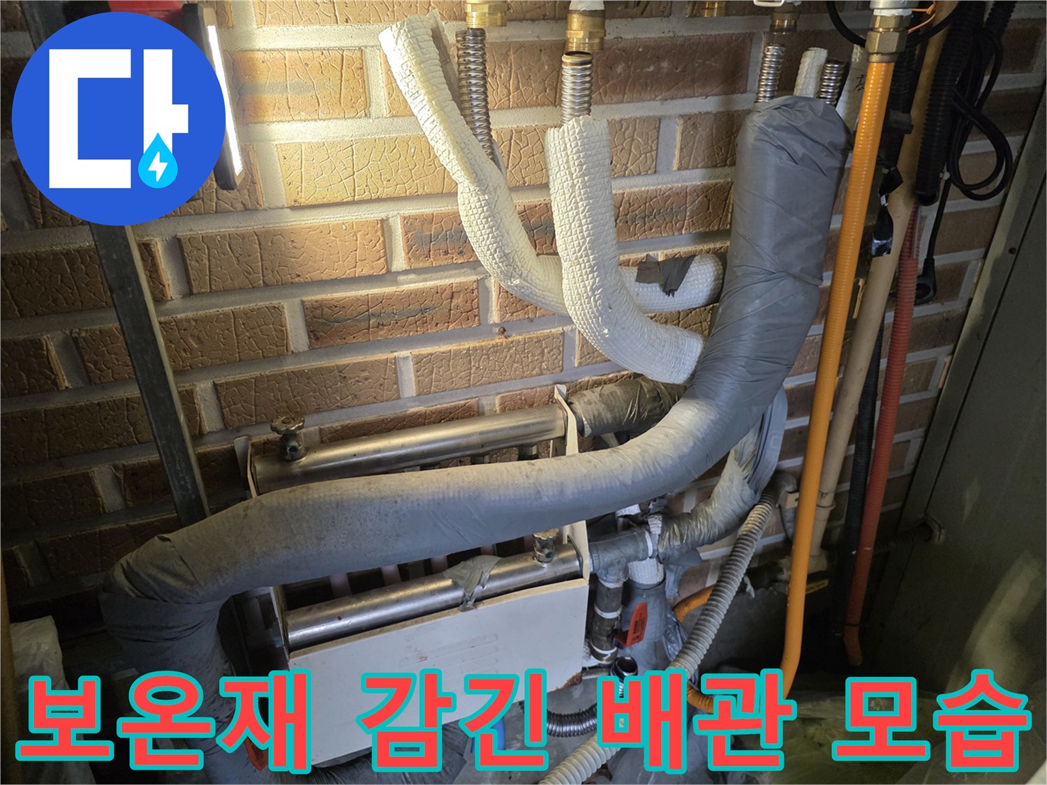 보온재로 마감된 배관과 금속 분배기가 설치된 현장 사진입니다.