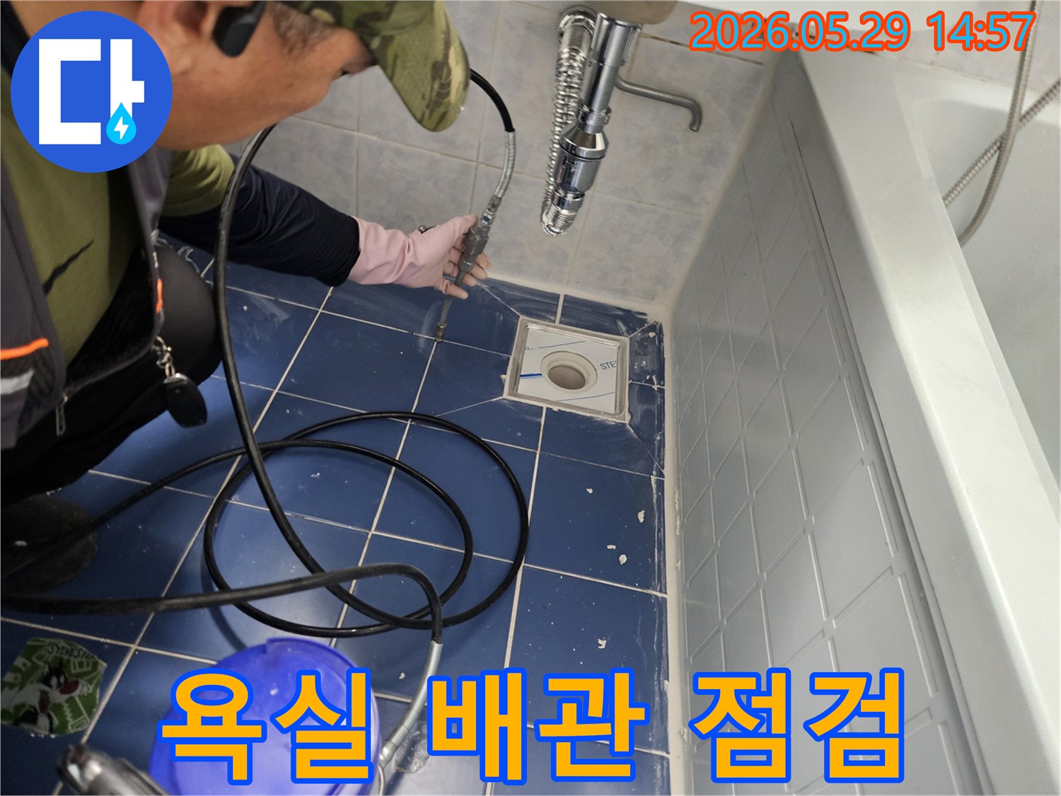 숙련된 엔지니어가 욕실 바닥 배수구에서 전문 장비를 사용하여 누수 원인을 정밀하게 점검하는 모습입니다-이 과정은 누수 지점을 정확히 찾아내기 위해 필수적입니다
