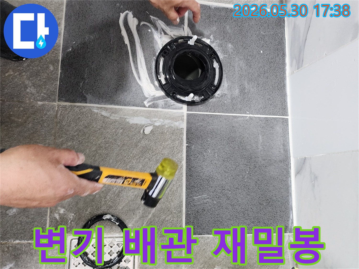 욕실 바닥의 변기 배관 연결 부위에서-누수 방지를 위한-정교한 밀봉 작업이-전문가에 의해 진행되고 있습니다.