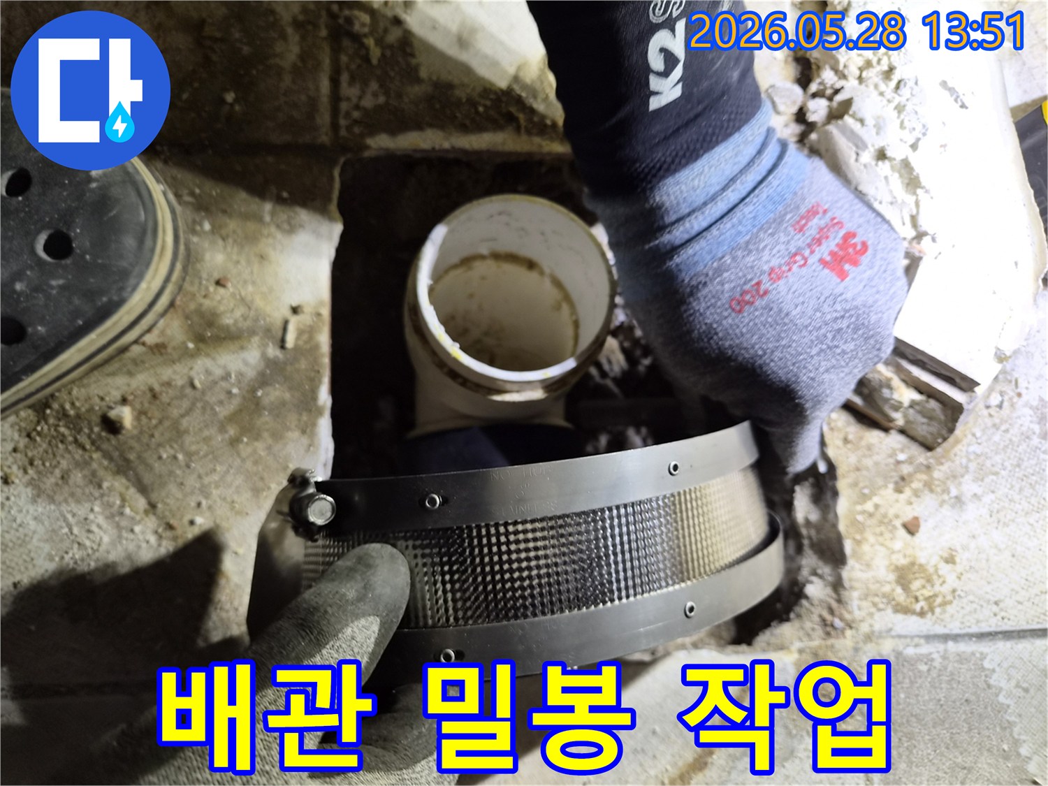 작업자가 안전 장갑을 끼고-손상된 배관의 연결 부위를-특수 밴드로 단단히 밀봉하는 모습입니다