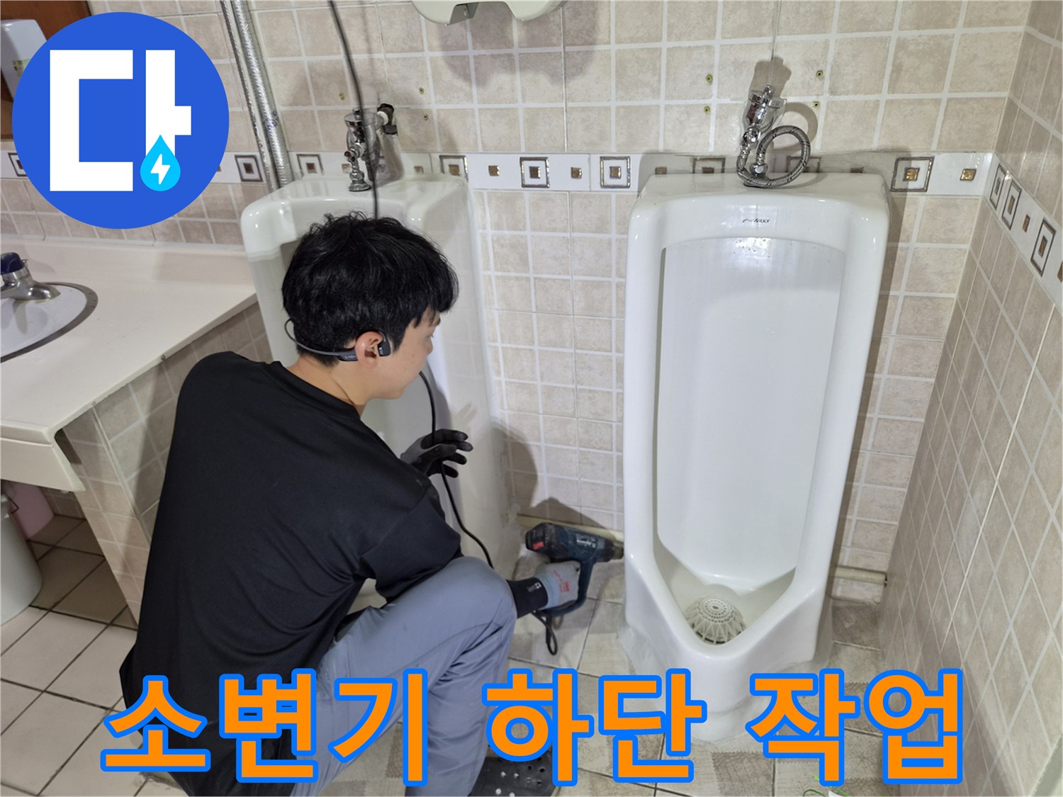 전동 드릴을 사용하여 소변기 주변 배관 부위를 점검하는 엔지니어