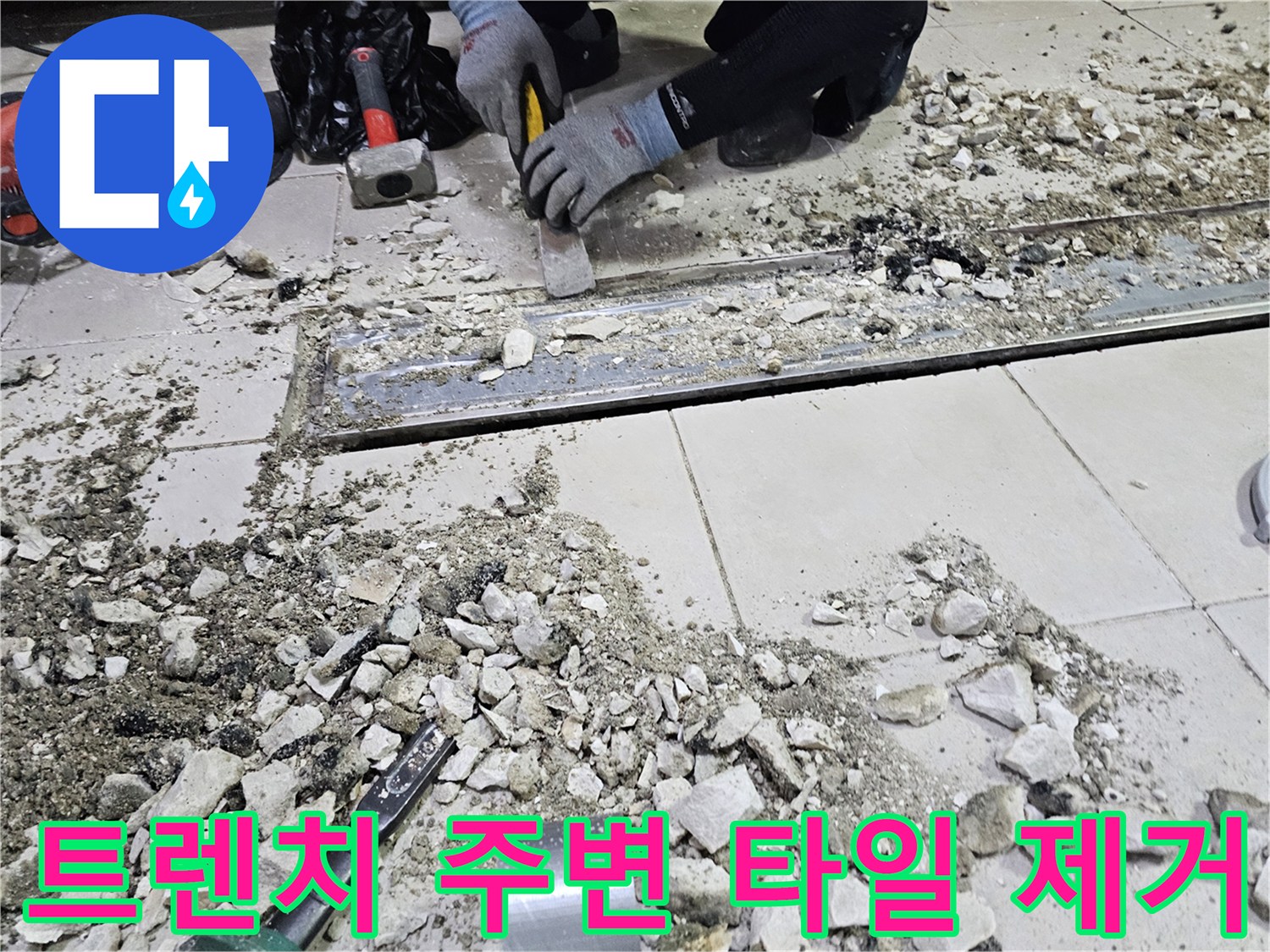 작업자가 장비를 사용하여 트렌치 근처의 깨진 타일을 정리하는 모습입니다.