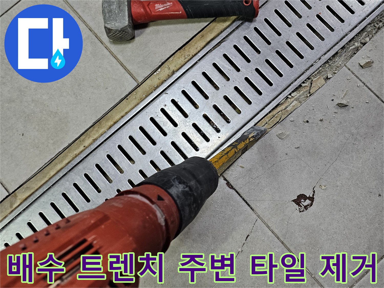 함마드릴과 망치를 사용하여 트렌치 옆 타일을 뜯어내는 장면