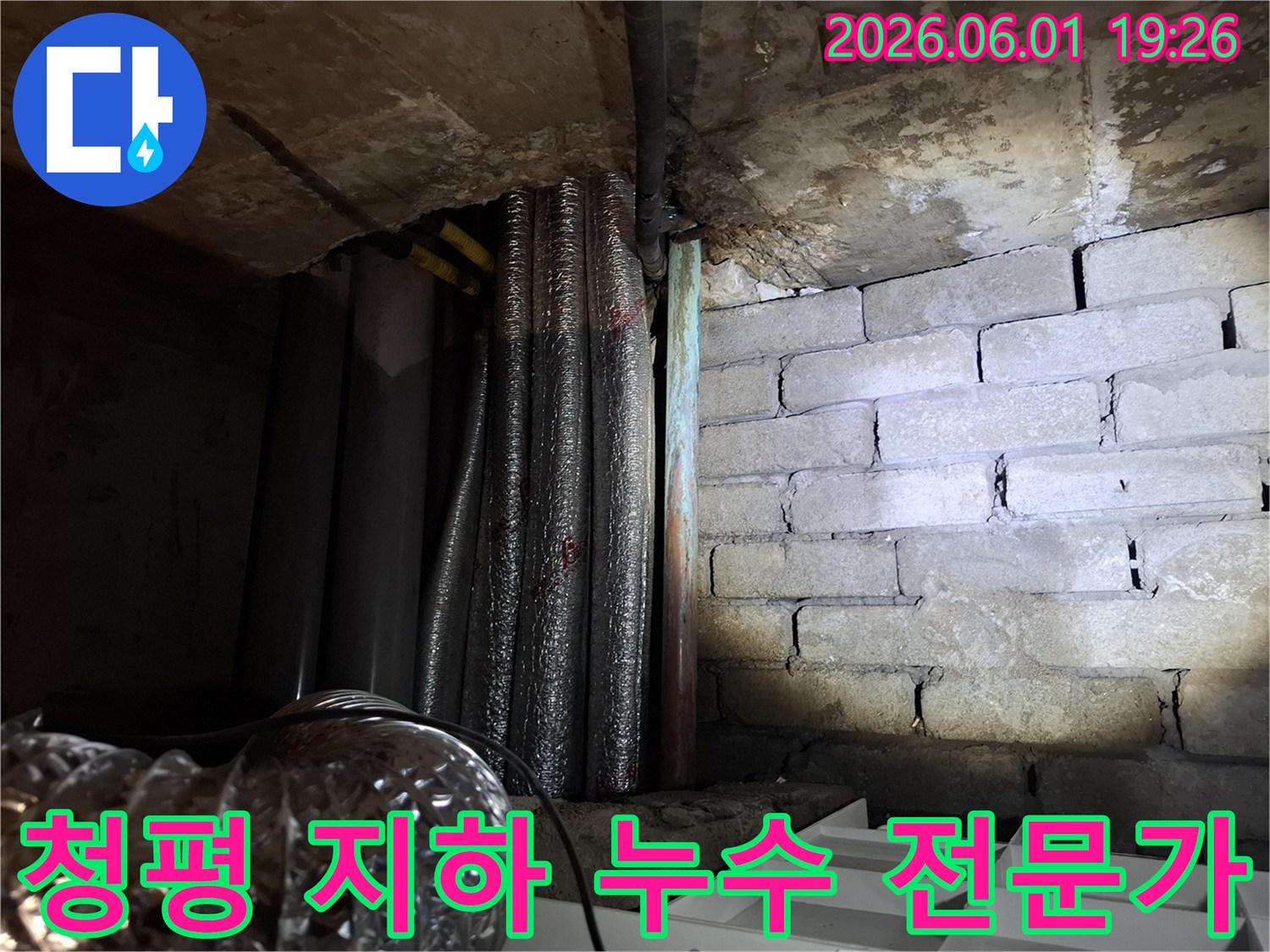 어두운 지하 공간에서-천장 배관과-벽돌 벽면의-누수 흔적을-확인하는 모습의-누수탐지 현장 사진입니다